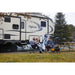 airskirts rv inflatable skirting kit lifestyle image reflection by grand design trailer on grass daytime with tubes placed underneath and two people sitting out front in chairs