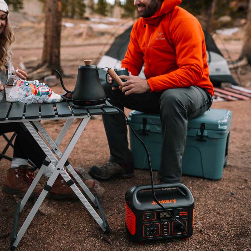 explorer 500 jackery lifestyle photo showing a person sitting on an ice chest while out camping. 