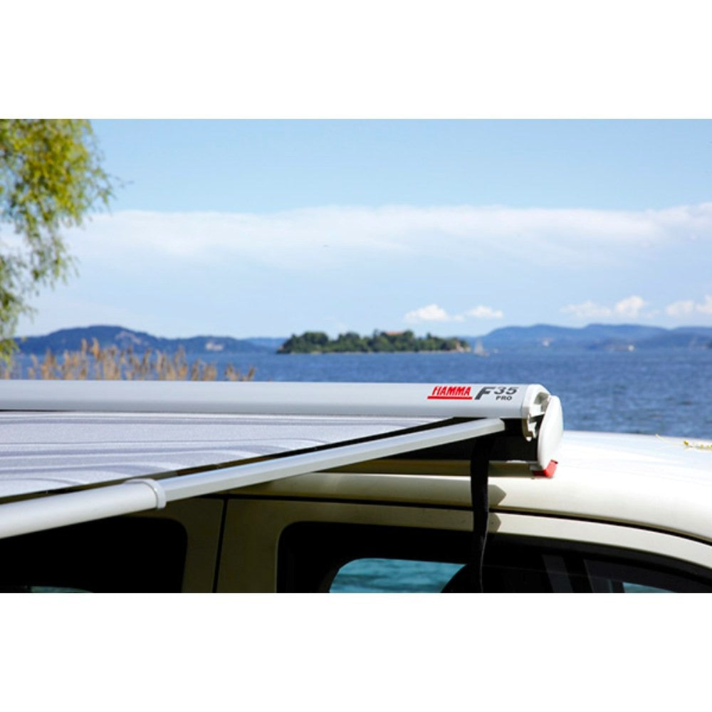 fiamma f35 pro 250 lifestyle closeup image that shows the titanium color awning fully extended on a vehicle in front of the lake